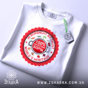 Футболка український борщ, біла, зображена зверху, фон світло-сірий, принт круглий червоний з написами 'IN BORSCHT WE TRUST', '100% УКРАЇНСЬКИЙ БОРЩ' та 'WORLD'S HERITAGE', прикріплена етикетка з зеленим шнурком.