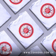 Футболка український борщ, біла, зображена на манекені, фон світло-сірий, принт круглий червоний з написами 'IN BORSCHT WE TRUST', '100% УКРАЇНСЬКИЙ БОРЩ' та 'WORLD'S HERITAGE', оточений малюнками овочів.