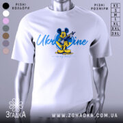 Футболка український дух, біла, зображена на манекені, фон градієнтний сірий, принт з мультяшним персонажем у жовтій та блакитній кольоровій гамі, напис 'Ukraine in my heart'.