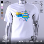 Футболка український хіпстер, біла, зображена на манекені з правого боку, фон нейтральний, принт з веселим персонажем у жовто-блакитному вбранні, напис "100% українським хіпстер".