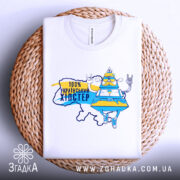 Футболка український хіпстер, біла, складена на плетеній основі, фон нейтральний, принт з персонажем у жовто-блакитному вбранні, напис "100% українським хіпстер".