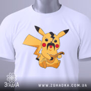 Футболка український пікачу, біла, складена на столі, фон світло-сірий, принт з жовтим пікачу з вусами та гітарою, на комірці є етикетка.
