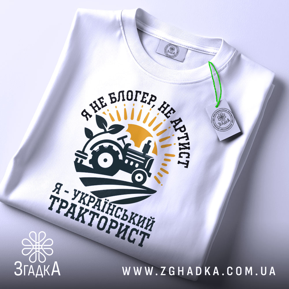 Футболка український тракторист, білого кольору, зображена в ракурсі зверху, фон світло-сірий, принт з трактором, сонцем і рослиною, текст чорного кольору, з етикеткою.