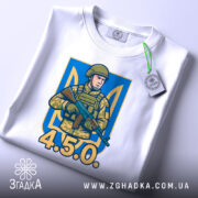 Футболка український воїн, біла, зображена зверху, на фоні світло-сірого, принт з військовим у камуфляжі, напис '4.5.0.' та етикетка з зеленим шнурком.