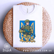 Футболка український воїн, біла, зображена зверху на плетеній кошику, фон світло-сірий, принт з військовим у камуфляжі та написом '4.5.0.' на синьому фоні.