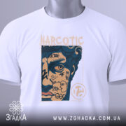 Футболка урбан стиль, біла, складена на поверхні, фон світло-сірий, принт з обличчям, що має графіті та напис "NARCOTIC", з зеленим ярликом.