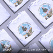 Футболка в комплекті з валідолом, білого кольору, зображена з фронтального ракурсу на манекені, фон нейтральний, принт з дівчиною в зеленій сукні на фоні поля з інструментами.