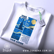 Футболка Ван Гог білого кольору, складена на поверхні, ракурс зверху, фон світло-сірий, принт з синіми та жовтими елементами, текст "1889 AT NIGHT" та ім'я "VAN GOGH", на футболці є етикетка з зеленим шнурком.