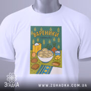 Футболка вареники білого кольору, складена на поверхні, з принтом вареників у мисці на зеленому фоні, прикрашена елементами, такими як цукор і овочі, з етикеткою, що звисає з коміра.