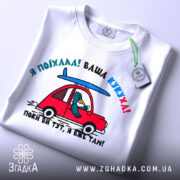 Футболка ваша кукуха, біла футболка, зображена зверху, з принтом червоного автомобіля та птаха, що сидить за кермом, фон світло-сірий, на футболці є етикетка.