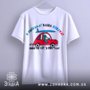 Футболка ваша кукуха, біла футболка на манекені, з принтом червоного автомобіля та птаха, що сидить за кермом, фон світло-сірий, принт яскравий і кольоровий.