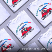 Футболка ваша кукуха, біла футболка на манекені, з принтом червоного автомобіля та птаха, що сидить за кермом, фон світло-сірий, принт яскравий і кольоровий.