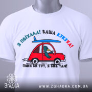 Футболка ваша кукуха, біла футболка, зображена зверху, з принтом червоного автомобіля та птаха, що сидить за кермом, фон світло-сірий, на футболці є етикетка.
