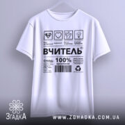 Футболка вчитель енергія, біла, підвішена на вішалці, фон світло-сірий, принт чорного кольору з символами та текстом, що описує склад і характеристики футболки.