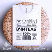 Футболка вчитель енергія, біла, складена на плетеній основі, фон світло-сірий, принт чорного кольору з символами та текстом, що описує склад і характеристики футболки.