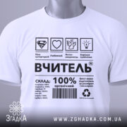 Футболка вчитель енергія, біла, складена на столі, фон світло-сірий, принт чорного кольору з символами та текстом, на футболці є етикетка з зеленим шнурком.