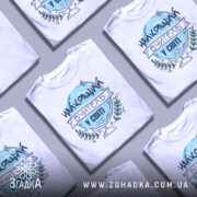 Футболка вчитель у світі, біла, зображена на манекені, фон світло-сірий, принт з написом 'НАЙКРАЩИЙ ВЧИТЕЛЬ У СВІТІ' у блакитному кольорі з елементами зелені.