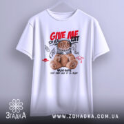 Футболка ведмедик хуліган білого кольору, підвішена на вішалці, з принтом ведмедика в космічному шоломі, на фоні світло-сірого кольору, деталі принта включають червоні та чорні елементи з написом 'GIVE ME SPACE EAT'.