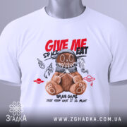 Футболка ведмедик хуліган білого кольору, складена на поверхні, з принтом ведмедика в космічному шоломі, на фоні світло-сірого кольору, деталі принта включають червоні та чорні елементи з написом 'GIVE ME SPACE EAT', з прикріпленою етикеткою.