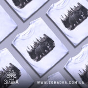 Футболка ведмідь Київ, біла, зображена на манекені, фон світло-сірий, принт з ведмедем на фоні київських будівель та лісу.