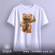 Футболка Ведмідь Пиво, біла футболка, підвішена на вішалці, з принтом ведмедя з вусами, який тримає ящик з пляшками пива, фон світло-сірий, деталі принта чіткі та кольорові.