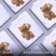 Футболка Ведмідь Пиво, біла футболка на манекені, з принтом ведмедя з вусами, який тримає ящик з пляшками пива, фон світло-сірий, деталі принта яскраві та чіткі.