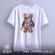 Футболка ведмідь термінатор, біла, підвішена на вішалці, фон світло-сірий, принт з ведмедем у сонцезахисних окулярах та механічною частиною, напис "НУ ЩО?" на червоному фоні.