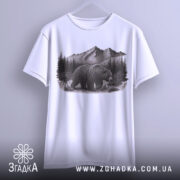 Футболка ведмідь у горах, біла, підвішена на вішалці, фон нейтральний, принт з ведмедем на фоні гір і лісу, деталі принта добре видимі.