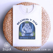 Футболка ведмідь у тілі, біла, складена на плетеній основі, фон білий, принт з ведмедем у зеленій шапці, що сидить за ноутбуком, текст під принтом - 'айтішник у душі'.