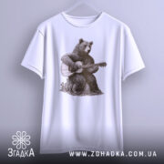 Футболка ведмідь з гітарою, біла, підвішена на вішалці, фон світло-сірий, принт з ведмедем, що грає на гітарі, деталі принта яскраві і чіткі.