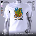 Футболка велоцираптор на велосипеді, біла, зображена з фронтального ракурсу, фон нейтральний, принт з велоцираптором на велосипеді з яскравими кольорами та містом на задньому плані.
