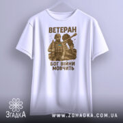 Футболка ветеран Бог війни, біла, зображена з фронтального ракурсу, фон світло-сірий, принт з військовим в бронежилеті та танком, текст коричневого кольору.