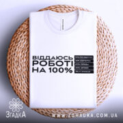 Футболка віддаюсь роботі, біла, розкладена на плетеній кошику, фон світло-сірий, принт чорного кольору з текстом про відсотки на дні тижня.