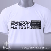 Футболка віддаюсь роботі, біла, розкладена на поверхні, фон світло-сірий, принт чорного кольору з текстом про відсотки на дні тижня, з зеленим ярликом.