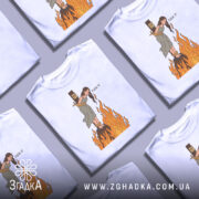 Футболка відьма на вогні, біла, зображена на манекені, фон світло-сірий, принт з відьмою, яка стоїть на вогняному стовпі, з написом 'FUCK IT'.