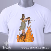 Футболка відьма на вогні, біла, зображена на столі, фон світло-сірий, принт з відьмою, яка стоїть на вогняному стовпі, з написом 'FUCK IT', на комірці є етикетка.
