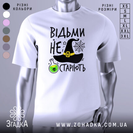 Футболка відьми не старіють, білого кольору, зображена з фронтального ракурсу на манекені, фон нейтральний, принт містить чорну відьомську шапку, зелену колбу з отрутою та текст.