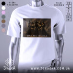 Футболка відьомський вайб, біла, зображена на манекені, фон сірий, принт з чотирма відьмами в чорних сукнях, текст 'GIRLS WILL BE GIRLS' під принтом.