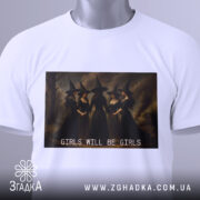 Футболка відьомський вайб, біла, складена на поверхні, фон світлий, принт з чотирма відьмами в чорних сукнях, текст 'GIRLS WILL BE GIRLS' під принтом, на комірці є етикетка.