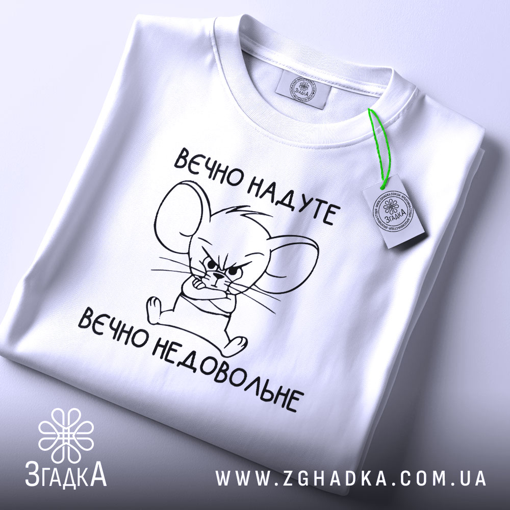 Футболка вєчно надуте, білого кольору, зображена в плоскому вигляді, фон світлий, принт з малюнком мишеняти з сердитим виразом обличчя та написом 'вєчно недовольне', на комірці прикріплена етикетка.
