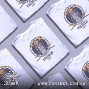 Футболка вікінги одін, біла, зображена з фронтального ракурсу на манекені, фон світло-сірий, принт з зображенням вікінга з рогатим шоломом та мечами, текст 'VIKINGS' під малюнком.