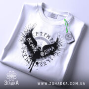 Футболка вісник одіна, біла, зображена зверху, на плоскій поверхні, фон світло-сірий, принт чорного кольору з крилами та написом 'VІСНІК ОДІНА', з зеленим ярликом.