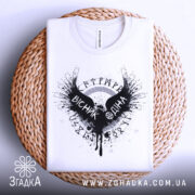 Футболка вісник одіна, біла, зображена зверху, на плоскій поверхні, фон світло-сірий, принт чорного кольору з крилами та написом 'VІСНІК ОДІНА', на плетеній основі.