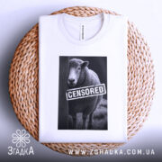 Футболка вівця цензоред, біла, складена на плетеній кошику, на фоні світлого градієнта, принт з овечкою та написом 'CENSORED' на чорному фоні.