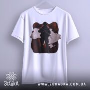 Футболка воїн України, біла, підвішена на вішалці, фон світлий, принт з силуетом солдата на червоному фоні з контуром України.