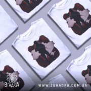 Футболка воїн України, біла, зображена на манекені, фон світлий, принт з силуетом солдата на червоному фоні з контуром України.