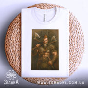 Футболка воїн вікінг білого кольору, зображена на плетеній кошику, фон світло-сірий, принт зображає м'язистого вікінга з сокирами, футболка складається на столі.