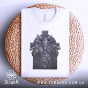 Футболка воїн вікінг білого кольору, складена на плетеній тарілці, принт з вікінгом з сокирами на фоні кельтського хреста, видно етикетку з логотипом бренду.