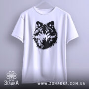 Футболка вовчий погляд, біла, підвішена на вішалці, фон світло-сірий, принт чорного кольору з деталізацією вовчої голови, видно округлі краї рукавів.
