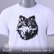 Футболка вовчий погляд, біла, складена на плоскій поверхні, фон світло-сірий, принт чорного кольору з зображенням голови вовка, на комірці видна етикетка.